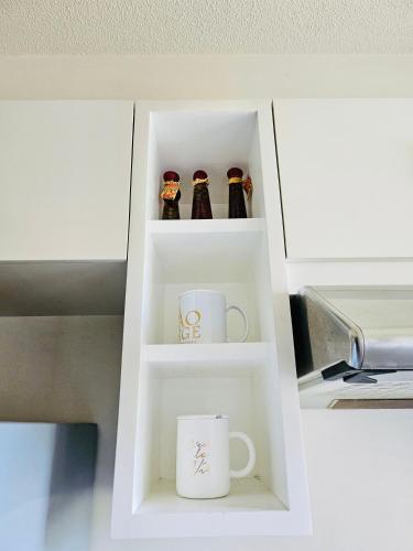 a white cabinet with two cups and mugs at Tropical Paradise @ One Oasis in Davao City+SM Davao in Davao City