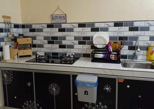a kitchen counter with a sink and a stove at Teratak Hannani Maryam Kampar ( Muslim Homestay) in Kampar