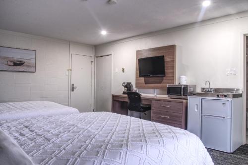 a hotel room with a bed and a desk with a microwave at Apollo Motel in Kapuskasing