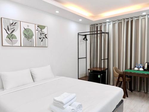 1 dormitorio con cama blanca y escritorio en Haha House en Ho Chi Minh