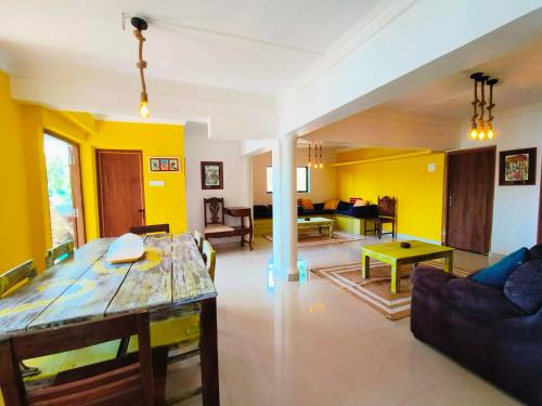 a living room with yellow walls and a table at Angels River Villa in Canacona