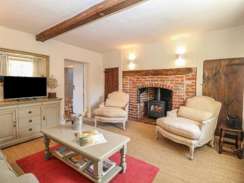 a living room with two chairs and a fireplace at Bridge Cottage in Norwich