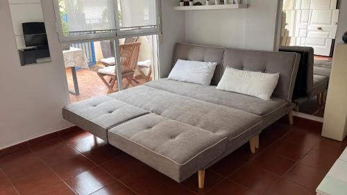 a couch with two pillows on it in a living room at PLAYA ALMARDA CORINTO, PISCINA, WIFI,2 TERRAZAS, BARBACOA,TRANQUILo in Sagunto