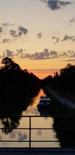 a boat traveling down a river at sunset at Rue Basse - village house overlooking the Pyrenees in Montréal