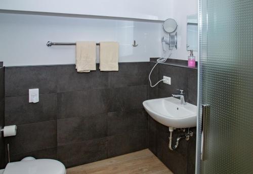 uma casa de banho com um lavatório, um WC e um espelho. em Hotel Zum Stern Spreewald em Werben