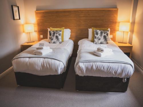 two beds in a hotel room with two lamps at Crossways in Wells