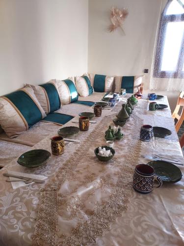 a long table with plates and bowls on it at Riad ma bonne étoile in Kasr Bounou