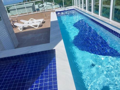 uma piscina com azulejos azuis ao lado de um edifício em MAKARANDUBA BEACH 304 - Piscinas Naturais e Coração de Porto em Porto de Galinhas