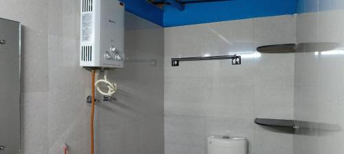 a bathroom with a toilet and a heater on the wall at Raagabynature home stay in Gendehalli