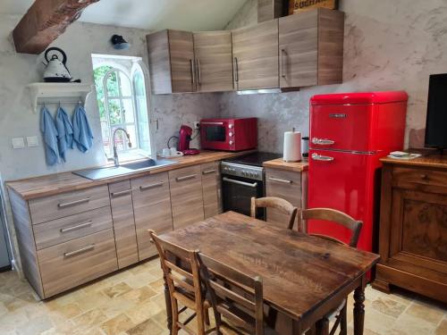 cocina con nevera roja y mesa de madera en PETIT GÎTE 18 ème tout confort en Saint-Germain-des-Fossés