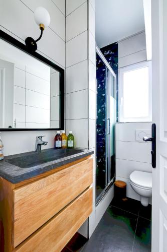 une salle de bain avec un lavabo, des toilettes et un miroir dans l'établissement Au centre de paris - 4pax, à Paris
