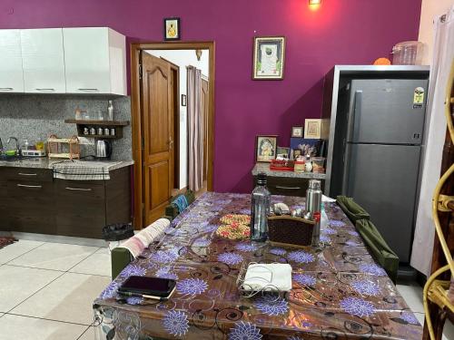 a kitchen with a table with a purple wall at Maass Homestay in Puducherry