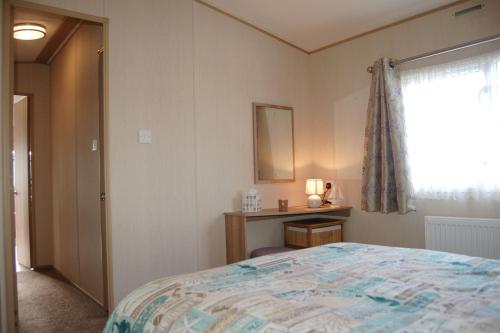 a bedroom with a bed and a window at Caravan 20 Neptune Caravan Park in Tywyn