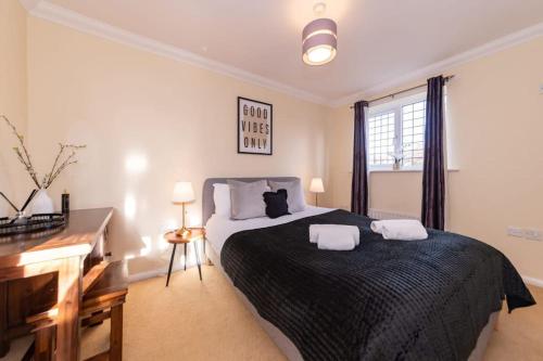 um quarto com uma cama grande com duas toalhas em Ratby House - Spacious 3 Bed with Garden & Parking em Earley