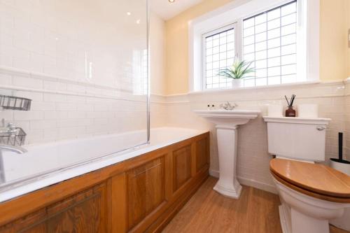 a bathroom with a tub and a toilet and a sink at Ratby House - Spacious 3 Bed with Garden & Parking in Earley