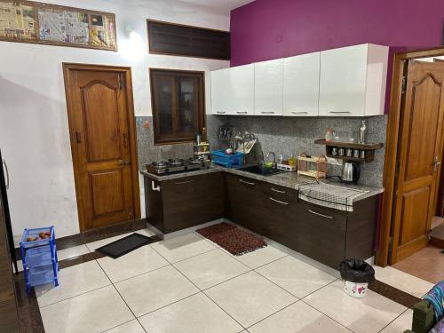 a kitchen with black counters and white cabinets and purple walls at Maass Homestay in Puducherry