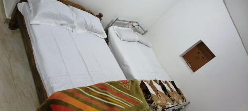 uma cama com lençóis brancos e uma toalha em Raagabynature home stay em Gendehalli