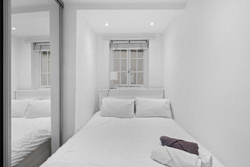 a white bedroom with a mirror and a bed at Londwell, Sloane Square Gem, Private Terrace Suite in London
