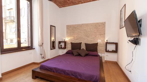 a bedroom with a purple bed and a flat screen tv at Ostilia Loft in Rome