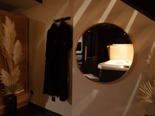 einen Spiegel an der Wand in einem Zimmer mit Bad in der Unterkunft Douceur du Charme - Love-room à Charmes entre Epinal et nancy in Charmes