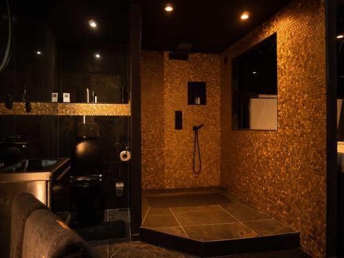 a bathroom with a shower with a tile wall at Douceur du Charme - Love-room à Charmes entre Epinal et nancy in Charmes