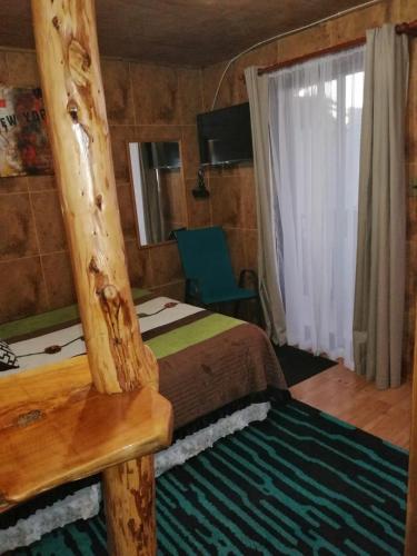 1 dormitorio con cama, ventana y silla en Departamentos Centro Pichilemu en Pichilemu