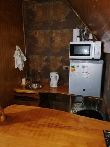 uma pequena cozinha com um micro-ondas em cima de um frigorífico em Departamentos Centro Pichilemu em Pichilemu