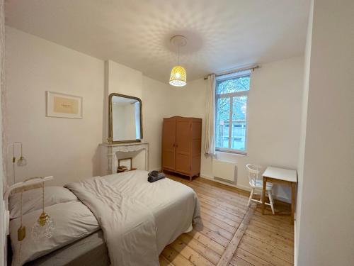 um quarto com uma cama, um espelho e uma mesa em L'Artoisienne • Parking sécurisé & Wifi fibre em Douai