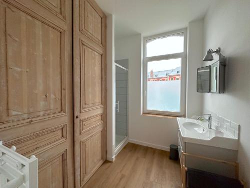 uma casa de banho com um lavatório e uma janela em L'Artoisienne • Parking sécurisé & Wifi fibre em Douai