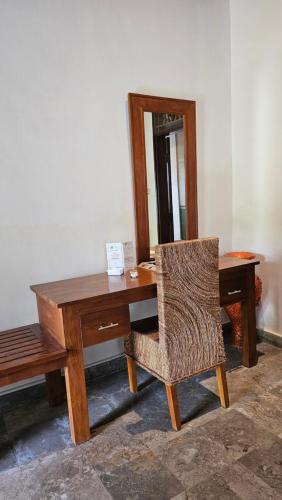 uma secretária de madeira com uma cadeira e um espelho em The Gana Ubud by Guru experience em Ubud