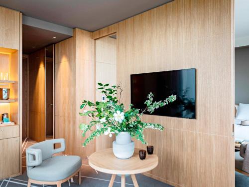 a living room with a table and a vase with flowers at Domaine de la Reine Margot Paris-Issy - MGallery Collection in Issy-les-Moulineaux