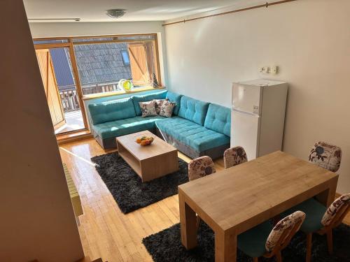 a living room with a blue couch and a table at BJELAŠNICA BEX APARTMANI 