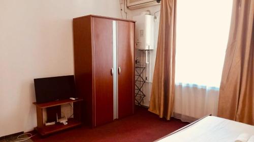 a bedroom with a wooden cabinet and a television at Heart of Old Town studio with self check in in Bucharest