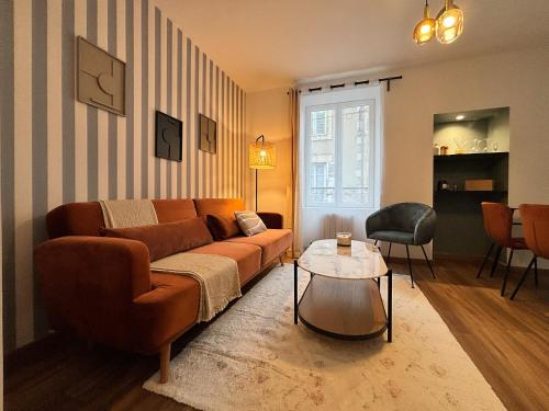 a living room with a couch and a table at Le Bouvault, style Appart'Hôtel , à Nevers proche Gare, services haut de gamme by PRIMO C0NCIERGERIE in Nevers