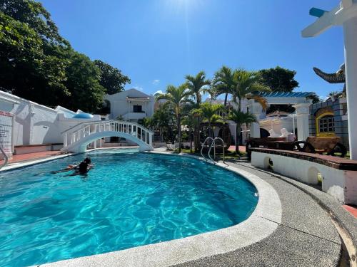 a person swimming in a swimming pool with a bridge at Villa Apolonia Resort in San Juan