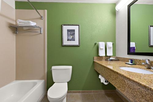 a green bathroom with a toilet and a sink at Sleep Inn & Suites near Joint Base Andrews-Washington Area in Morningside