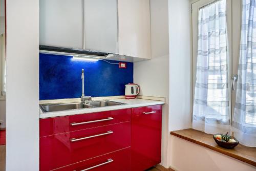 - une cuisine avec des placards rouges et un évier dans l'établissement Balconi Rossi Borgo Valsugana, à Borgo