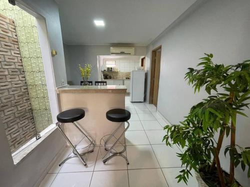 - une cuisine avec deux tabourets et un comptoir dans une pièce dans l'établissement Pousada da Nicole, à Canindé de São Francisco