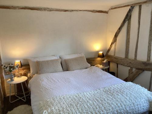 a bedroom with a large bed with white sheets and pillows at Black Sheep Cottage in Saxmundham