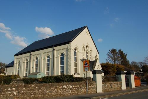 a white church with a black roof on a street at Ty Capel in Tywyn in Tywyn