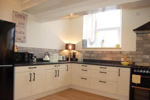 a kitchen with white cabinets and a black refrigerator at Ty Capel in Tywyn in Tywyn
