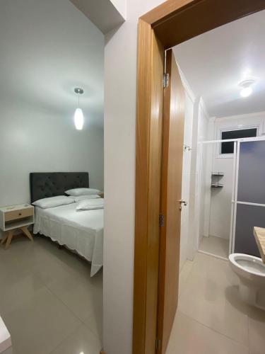 a bedroom with a bed and a bathroom with a sink at Apartamento NOVO completo com garagem e suíte no centro NÃO ACEITAMOS ANIMAIS in Capão da Canoa