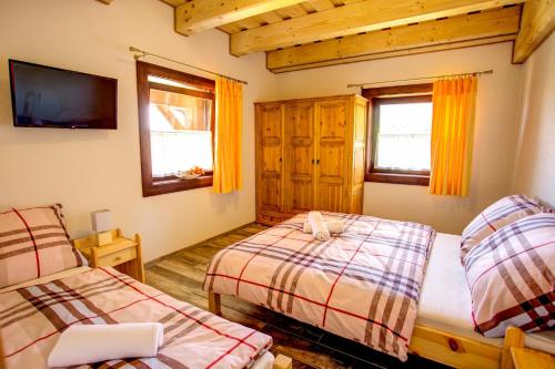 a bedroom with two beds and a flat screen tv at Drevenica pod Sitieňom 1 in Lazisko