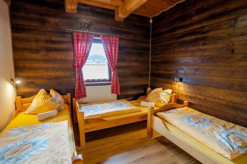 1 dormitorio con 2 camas y ventana en Drevenica pod Sitieňom 1, en Lazisko