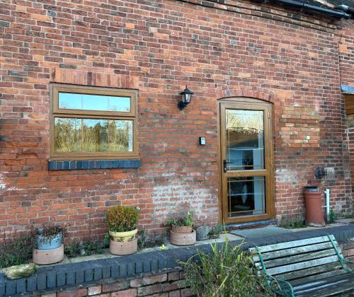 a brick building with potted plants next to a door at The Byre in Lichfield