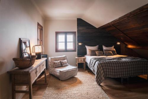 - une chambre avec un grand lit et une chaise dans l'établissement Le Refuge du Grand Hôtel - Altitude 1900 m, à Saint-Chaffrey