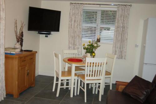 a dining room with a table and chairs and a television at Anneddle Cottage in Talybont, near Barmouth in Talybont