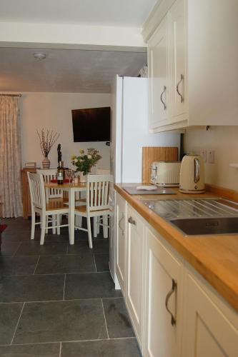 a kitchen with white cabinets and a table with chairs at Anneddle Cottage in Talybont, near Barmouth in Talybont
