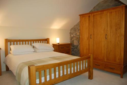 a bedroom with a bed and a wooden cabinet at Anneddle Cottage in Talybont, near Barmouth in Talybont