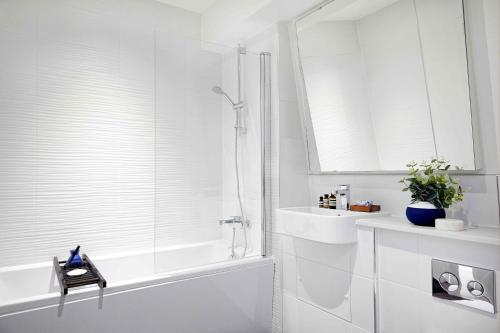 a white bathroom with a shower and a sink at Cosy Central Bedford Apt - Free Parking, Gym, Netflix & Sky in Bedford